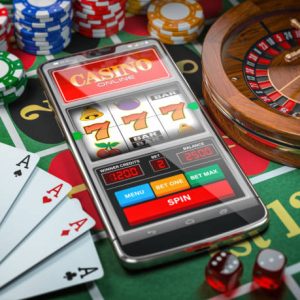 Casino online. Smartphone or mobile phone, slot machine, dice, cards and roulette on a green table in casino. 3d illustration